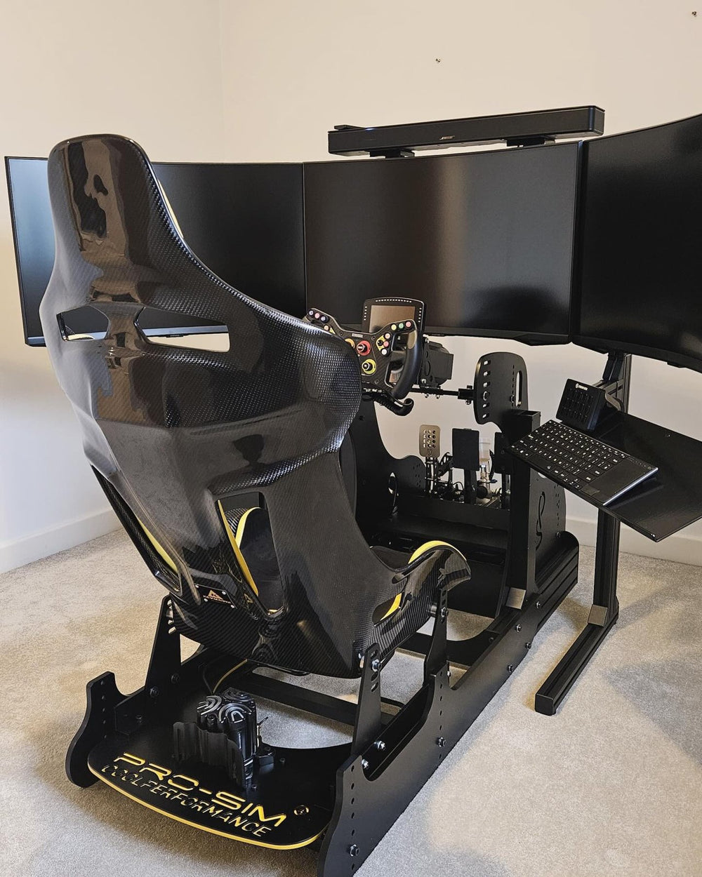 Black GT simulator with yellow details and triple monitors in a home