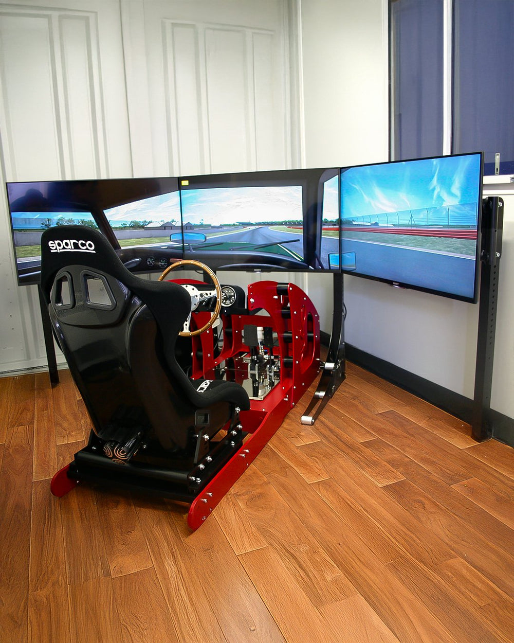 Red GT Pro classic car simulator with wooden steering wheel, Sparco seat and triple 55 inch monitors in a home