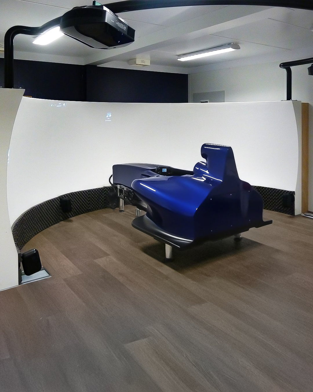 Blue full size F1 cockpit simulator in front of a curved projection screen