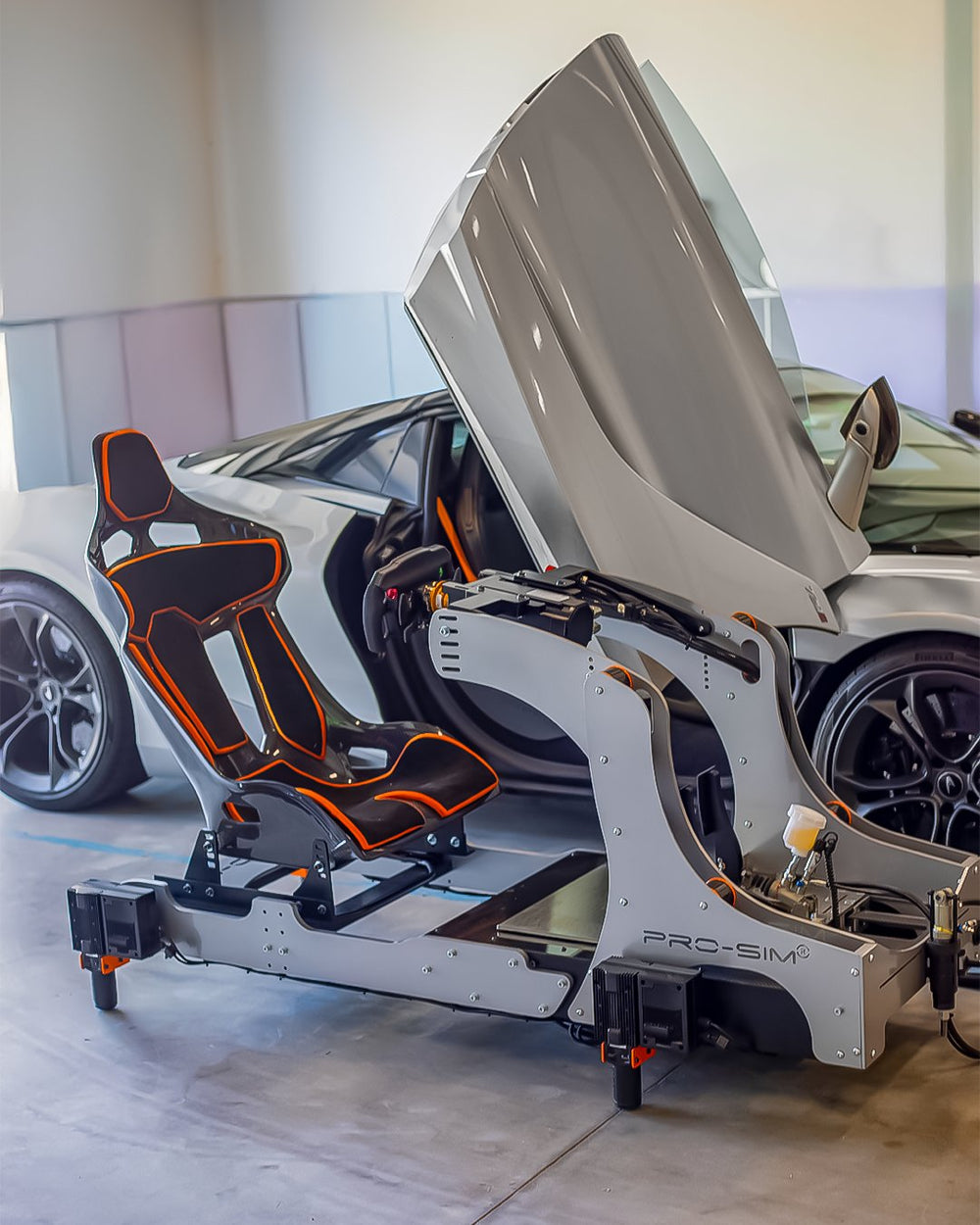 GT Pro in McLaren titanium silver with orange seat beside the McLaren it matches, in a home garage, USA