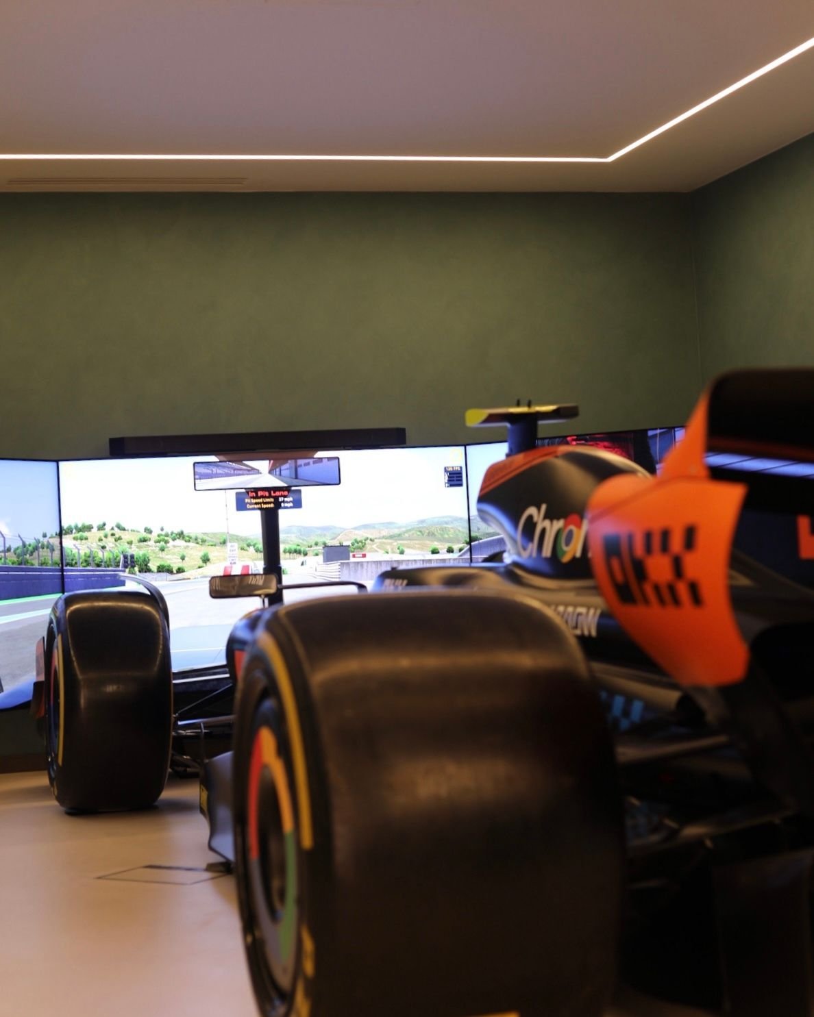 Full size McLaren replica F1 car simulator with wraparound screens in a home sim room