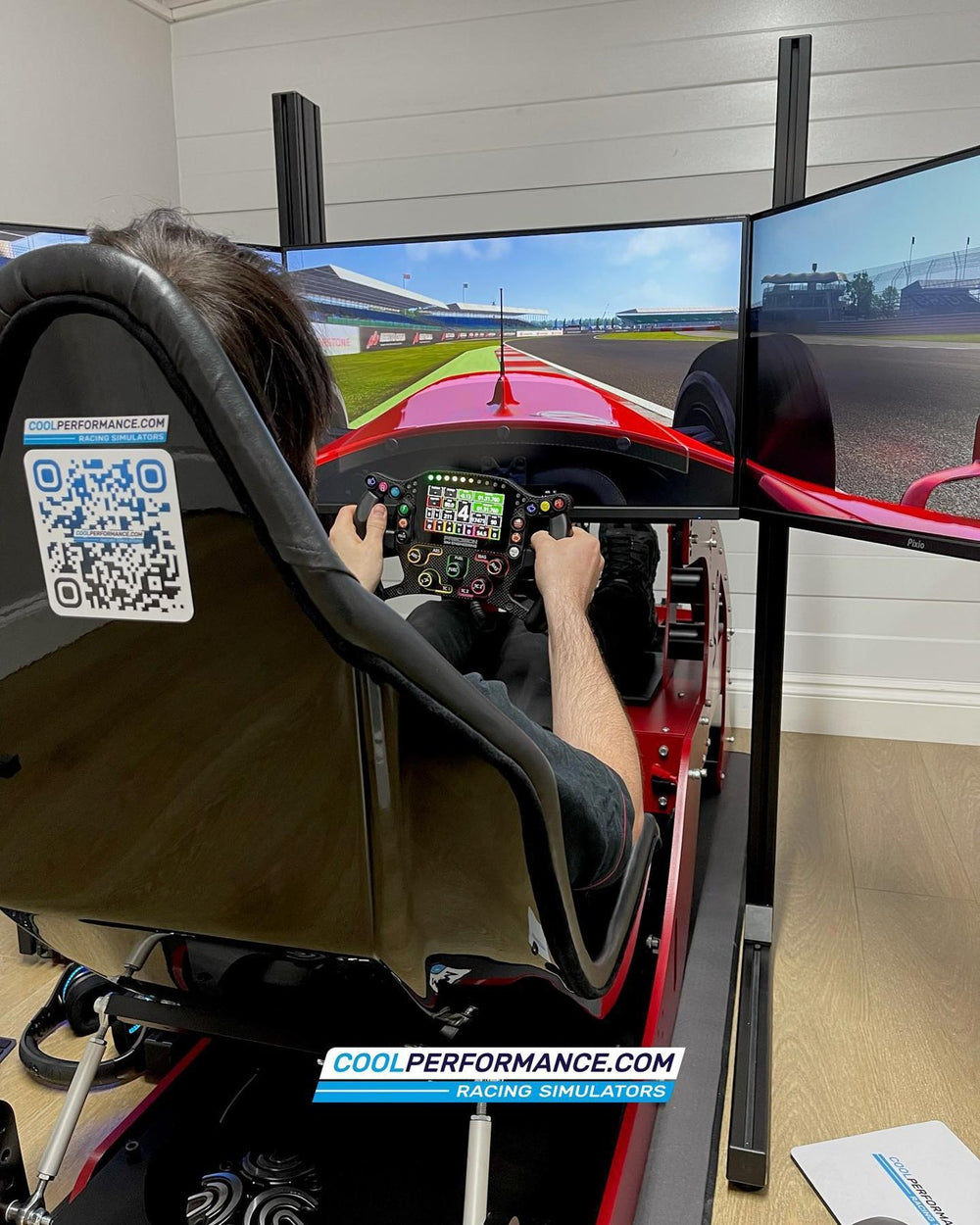 Red and black Formula simulator with triple screens installed at Yiannimize, UK